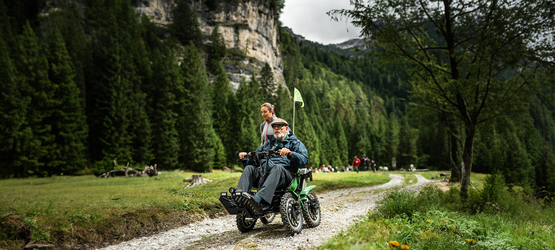 Un uomo in quad bike si allontana dalla sede del concerto, probabilmente finito da poco. Una ragazza cammina al suo fianco, chiacchierando. Il cielo è grigio e l’aria dev’essere fresca. Il verde degli alberi sullo sfondo è scuro e intenso.