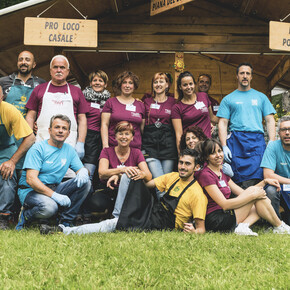 Gruppenfoto mit einigen Freiwilligen der Veranstaltung Tutti #fuori (alle #nachdraußen), dem großen Wanderfestival der Pro Loco im Trentino. Die Farben der T-Shirts, die sie tragen, verraten uns, dass es sich um Freiwillige von verschiedenen Pro Locos handelt. Aber hier arbeiten sie zusammen, und gemeinsam feiern sie ihr Engagement.