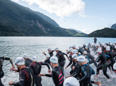 A group of X-Terra participants wearing wetsuits and swimming caps dive into Lake Molveno 