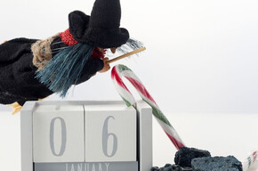 Nella foto si vede un pupazzetto della befana con carbone e caramelle e un calendario che indica il 6 di gennaio