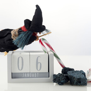 Nella foto si vede un pupazzetto della befana con carbone e caramelle e un calendario che indica il 6 di gennaio