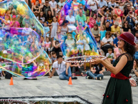 L'immagine mostra l'artista mentre crea bolle giganti