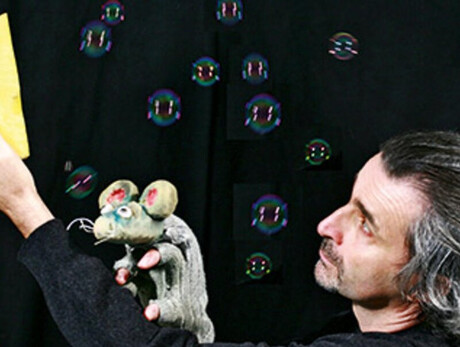 Nell'immagine si vede il topo che cerca di raggiungere il formaggio e sullo sfondo tante bolle di sapone