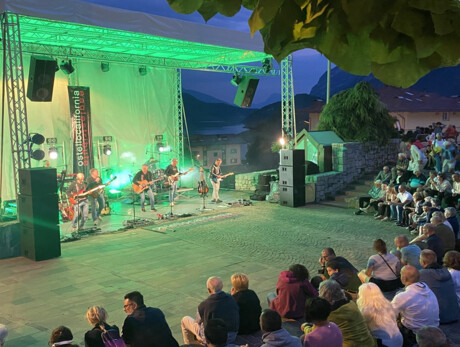 Image of the band playing and singing in the church square in Molveno in front of the listening crowd 