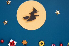 Nell'immagine si vede la befana disegnata su cartincino , mentre vola con la scopa nella luna piena. In basso dei dolcetti decorano il foglio