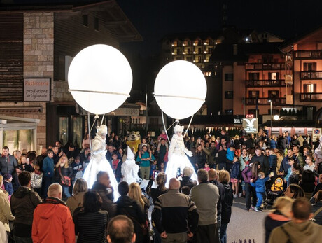 L'immagine mostra le vie del centro di Andalo durante la sera con artisti di strada e le persone che osservano lo spettacolo