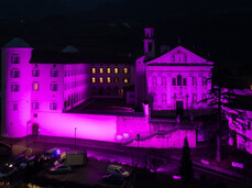 Night view of the Church of San Michele Arcangelo and the Mach Foundation, both illuminated in pink for the 'Italia in Rosa' initiative.