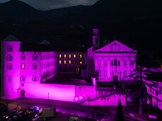 Night view of the Church of San Michele Arcangelo and the Mach Foundation, both illuminated in pink for the 'Italia in Rosa' initiative.