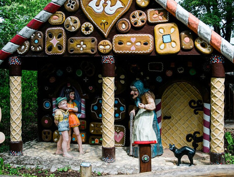 L'immagine mostra la casetta di dolci con la strega e Hansel e Gretel che le parlano