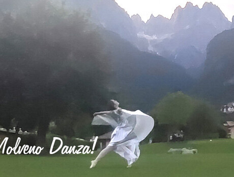 The image shows a dancer dressed in white by the lakeside.