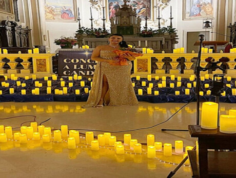 A WELL-DRESSED WOMAN AMIDST MANY CANDLES INSIDE A CHURCH