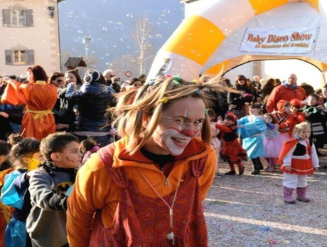 A friendly clown playing with children in the square with confetti and sparklers.