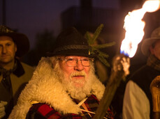 Three men dressed as ancient shepherds take part in the Canta della Stella. In the foreground, the eldest, with a long white beard, holds a lit torch to provide light.