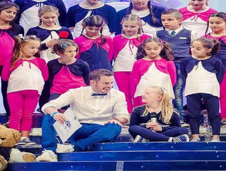 Children on stage, ready to sing a song.