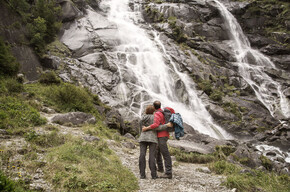 Couple trekking with stops to admire waterfall